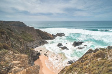 Portekiz 'in Odemira bölgesindeki Atlantik Okyanusu' nun dalgalarıyla sulanan sarı-turuncu kumlara sarp kayalıklar düşüyor. Balıkçı Yolu 'nun ayak izlerinde, Rota Vicentina..