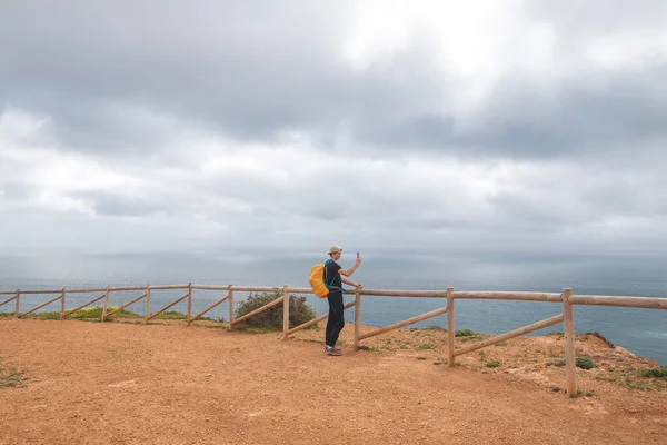 stock image Traveller takes a picture on his mobile phone at the top of Atalaia hill overlooking the city of Luz and the beaches of the Atlantic Ocean in the Algarve region of southern Portugal.