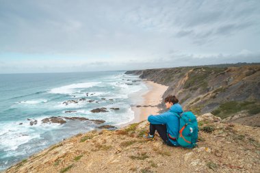 Genç adam, Portekiz 'in güneybatısındaki ünlü Praia da Carreagem plajının üzerinde, Odemira bölgesinin Aljezur kasabası yakınlarında yer almaktadır. Balıkçı Patikası 'nda dolaşırken.