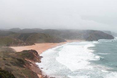 Portekiz 'in Odemira bölgesindeki kayalık kayalıklardan ve kumlu plajlardan oluşan batı kıyı şeridi. Yağmurlu günlerde Balıkçı patikasında dolaşmak.