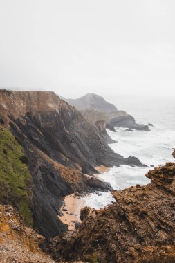 Portekiz 'in güneybatısındaki Algarve bölgesinde Atlantik Okyanusu' na batan yüksek kireçtaşı kayalıkları. Yağmurlu bir hava. Balıkçı Patikası 'nda dolaşırken.