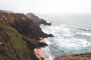 Portekiz 'in güneybatısındaki Algarve bölgesinde Atlantik Okyanusu' na batan yüksek kireçtaşı kayalıkları. Yağmurlu bir hava. Balıkçı Patikası 'nda dolaşırken.