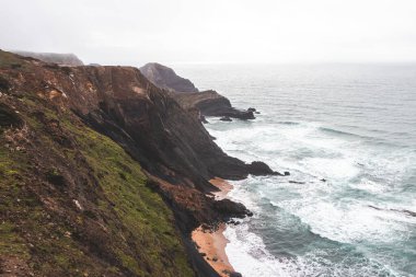 Portekiz 'in güneybatısındaki Algarve bölgesinde Atlantik Okyanusu' na batan yüksek kireçtaşı kayalıkları. Yağmurlu bir hava. Balıkçı Patikası 'nda dolaşırken.