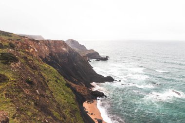 Portekiz 'in güneybatısındaki Algarve bölgesinde Atlantik Okyanusu' na batan yüksek kireçtaşı kayalıkları. Yağmurlu bir hava. Balıkçı Patikası 'nda dolaşırken.