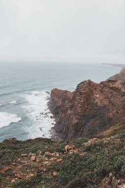 Portekiz 'in güneybatısındaki Algarve bölgesinde Atlantik Okyanusu' na batan yüksek kireçtaşı kayalıkları. Yağmurlu bir hava. Balıkçı Patikası 'nda dolaşırken.