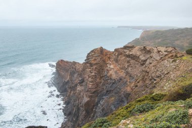 Bir uçurumun kenarında duran maceraperest adam, Portekiz 'in güneybatısındaki Odemira bölgesindeki Atlantik kıyısının manzarasının keyfini çıkarıyor. Rota Vicentina 'da dolaşıyorum..