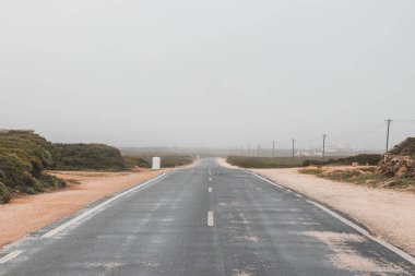 Cabo de Sao Vicente 'deki Deniz fenerine giden tozlu yol. Portekiz, Algarve bölgesindeki Sagres yolu..