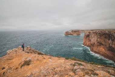 Siyah saçlı maceracı, Portekiz 'in güneybatısındaki Cabo de Sao Vicente Burnu' nun sonunda duruyor. İnsan özgürlüğünün tadını çıkarıyor. Balıkçı Yolu 'nun Gezgini.