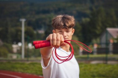 Kahverengi saçlı, atletik yapılı bir çocuk, atlama halatını dayanıklılığı ve atlama gücünü arttırmak için en iyi araçlardan biri olarak tanıtıyor..