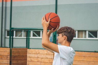 Genç yetenekli basketbolcu dışarıda basketbol oynuyor ve gelecek maçlar ve zor durumlar için antrenman yapıyor. Sezona hazırlanıyorum. Sepete ateş ediyorum..