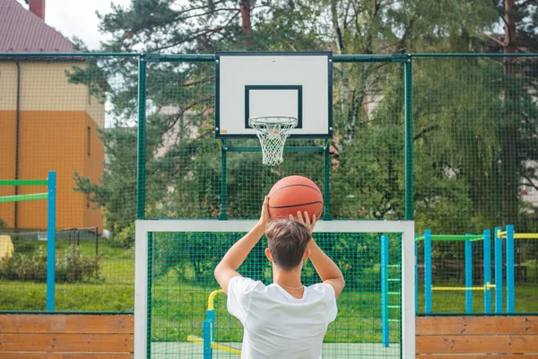 Genç yetenekli basketbolcu dışarıda basketbol oynuyor ve gelecek maçlar ve zor durumlar için antrenman yapıyor. Sezona hazırlanıyorum. Sepete ateş ediyorum..