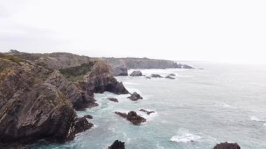 Dalgalar yağmurlu günlerde batı Portekiz kıyılarının kayalık burunlarına çarpar. Yukarıdan bak. 4k video