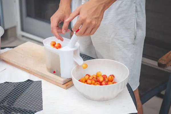 stock image Worker uses a simple tool to extract pits from fresh cherries and prepare them for further use. Manual work with fruit. Seasonal work.