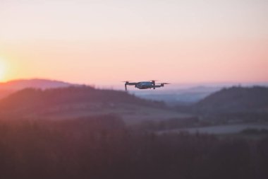 Gün batımında seyyar drone çalışıyor. Fotoğrafçılık ve havacılıkta teknolojik yenilik. Hava görüntüsü video kaydı. Uçan aygıt.