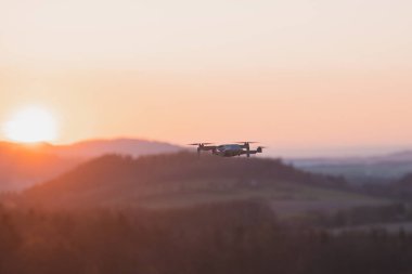 Gün batımında seyyar drone çalışıyor. Fotoğrafçılık ve havacılıkta teknolojik yenilik. Hava görüntüsü video kaydı. Uçan aygıt.