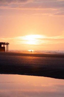 Batı Belçika 'nın Oostende sahillerinde gün batımında genç bir çiftin romantik yürüyüşü. Sevgi ve bağlılık. Su havuzundaki yansıma..