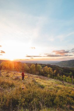Kırmızı ve siyah gömlekli maceraperest ve gezgin gün batımını seyrediyor Raskovice ormanını aydınlatıyor, Beskydy dağları, Çek Cumhuriyeti. Orta Avrupa 'nın büyüleyici doğası.