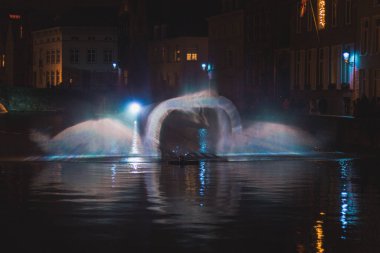 Belçika 'nın tarihi Bruges bölgesindeki su kanalında Kuğu Dansı şeklinde Noel ışığı gösterisi. Romantik sahne.