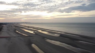 Günbatımı, kumlu plajlar ve Fransa 'nın Dunkirk yakınlarındaki sonsuz okyanus manzarası. Plage de Zuydcoote akşam ışığında