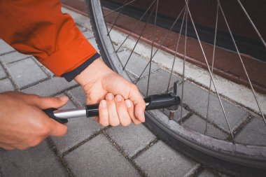 Adam sezon için motosikletini hazırlıyor. Bir el bisikleti pompasıyla motorun iç tüpünü patlatmak. Açık hava sporu. Düzenli bakım.