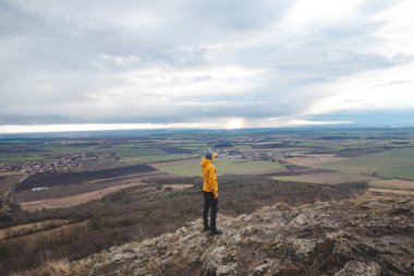 Sarı ceketli gezgin Rip Dağı 'nın tepesinde duruyor ve Prag şehrini işaret ediyor. Çek ülkesini keşfetmek.