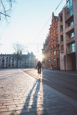 Ghent, Belçika 'nın şehir merkezinde güneş doğarken bisikletle işe koşan bir adam. Ana ulaşım aracı olarak bisikleti kullanın. Ekolojik mühendislik.