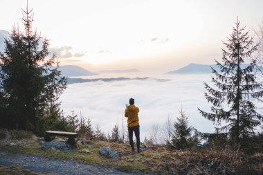 Maceracı gün batımını ve aşağıdaki bulutları yakalamak için cep telefonuyla fotoğraf çeker. Teknoloji ile anıları yakalamak. Beskydy Dağları, Çek Cumhuriyeti.
