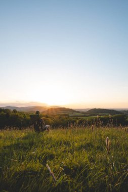 Ekose gömlekli genç adam seyyar bir hafif koltukta oturur, vadinin manzarasının ve ufukta batan güneşin tadını çıkarır. Beskydy Dağları, Çek Cumhuriyeti.
