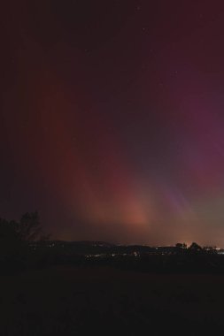Çek Cumhuriyeti üzerinde dans eden pembe, sarı ve kırmızı aurora. Büyük bir güneş fırtınası. Jeomanyetik bir fırtınanın altında gece gökyüzü pembeye dönüyor. Çek Cumhuriyeti 'nde bir mucize. Kuzey ışıkları.