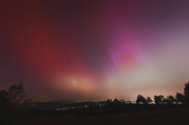 Çek Cumhuriyeti üzerinde dans eden pembe, sarı ve kırmızı aurora. Büyük bir güneş fırtınası. Jeomanyetik bir fırtınanın altında gece gökyüzü pembeye dönüyor. Çek Cumhuriyeti 'nde bir mucize. Kuzey ışıkları.