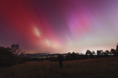 Çek Cumhuriyeti üzerinde dans eden pembe, sarı ve kırmızı aurora. Büyük bir güneş fırtınası. Jeomanyetik bir fırtınanın altında gece gökyüzü pembeye dönüyor. Çek Cumhuriyeti 'nde bir mucize. Kuzey ışıkları.