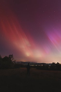 Çek Cumhuriyeti üzerinde dans eden pembe, sarı ve kırmızı aurora. Büyük bir güneş fırtınası. Jeomanyetik bir fırtınanın altında gece gökyüzü pembeye dönüyor. Çek Cumhuriyeti 'nde bir mucize. Kuzey ışıkları.