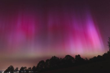 Çek Cumhuriyeti üzerinde dans eden pembe, sarı ve kırmızı aurora. Büyük bir güneş fırtınası. Jeomanyetik bir fırtınanın altında gece gökyüzü pembeye dönüyor. Çek Cumhuriyeti 'nde bir mucize. Kuzey ışıkları.