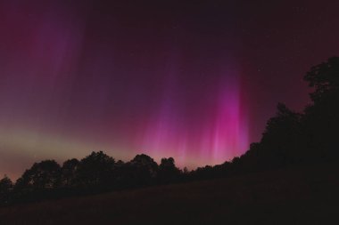 Çek Cumhuriyeti üzerinde dans eden pembe, sarı ve kırmızı aurora. Büyük bir güneş fırtınası. Jeomanyetik bir fırtınanın altında gece gökyüzü pembeye dönüyor. Çek Cumhuriyeti 'nde bir mucize. Kuzey ışıkları.
