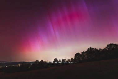 Çek Cumhuriyeti üzerinde dans eden pembe, sarı ve kırmızı aurora. Büyük bir güneş fırtınası. Jeomanyetik bir fırtınanın altında gece gökyüzü pembeye dönüyor. Çek Cumhuriyeti 'nde bir mucize. Kuzey ışıkları.