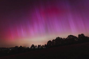 Çek Cumhuriyeti üzerinde dans eden pembe, sarı ve kırmızı aurora. Büyük bir güneş fırtınası. Jeomanyetik bir fırtınanın altında gece gökyüzü pembeye dönüyor. Çek Cumhuriyeti 'nde bir mucize. Kuzey ışıkları.