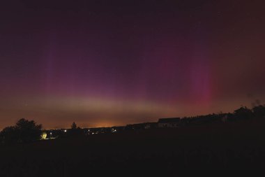 Çek Cumhuriyeti üzerinde dans eden pembe, sarı ve kırmızı aurora. Büyük bir güneş fırtınası. Jeomanyetik bir fırtınanın altında gece gökyüzü pembeye dönüyor. Çek Cumhuriyeti 'nde bir mucize. Kuzey ışıkları.