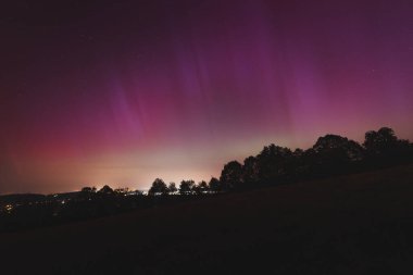 Çek Cumhuriyeti üzerinde dans eden pembe, sarı ve kırmızı aurora. Büyük bir güneş fırtınası. Jeomanyetik bir fırtınanın altında gece gökyüzü pembeye dönüyor. Çek Cumhuriyeti 'nde bir mucize. Kuzey ışıkları.
