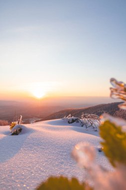 Çek Cumhuriyeti 'nin doğusundaki Moravian-Silesian Beskids' da kış günbatımı. Karla kaplı tepeler, canlı turuncu-pembe gökyüzü, dingin doğa, ve buzlu ağaçlar cennet gibi bir kış manzarası yaratır..