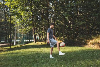 Siyah saçlı atlet çimlerde dostça bir futbol maçı oynar. Amatör spor. Topla oynayan bir adam. Salya sürme alıştırması. Spor yaşam tarzı.