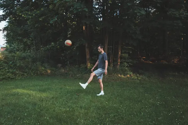 Siyah saçlı atlet çimlerde dostça bir futbol maçı oynar. Amatör spor. Topla oynayan bir adam. Salya sürme alıştırması. Spor yaşam tarzı.