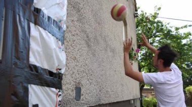 Voleybol oyuncusu duvarda bir topla voleybol antrenmanı yapıyor. Pas ver, vur, kaz. Hareketin otomasyonu. Özel tatbikat