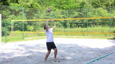 Voleybol oyuncusu voleybol sahasında bir topla voleybol antrenmanı yapıyor. Pas ver, vur, kaz. Hareketin otomasyonu. Özel tatbikat