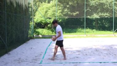Voleybol plaj oyuncusu bir plaj kortunda servis yapıyor. Yüzen servis. Voleybol yetenekleri. Amatör spor. 4k video