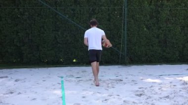 Voleybol plaj oyuncusu bir plaj kortunda servis yapıyor. Yüzen servis. Voleybol yetenekleri. Amatör spor. 4k video