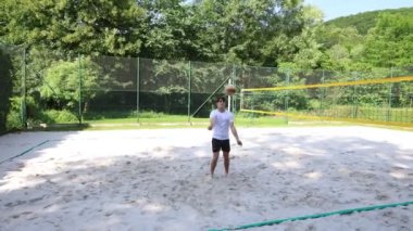 Voleybol oyuncusu voleybol sahasında bir topla voleybol antrenmanı yapıyor. Pas ver, vur, kaz. Hareketin otomasyonu. Özel tatbikat