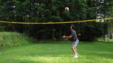 Voleybol oyuncusu, dışarıda çim sahada topla voleybol antrenmanı yapıyor. Pas ver, vur, kaz. Hareketin Otomatik Olması