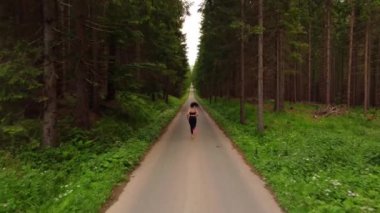 Genç bayan spor giyim sporcuları temiz havada orman yolunda koşuyor. Koşu temposunda antrenman. 4k video