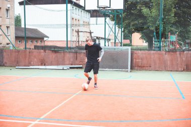 Genç adam dışarıda bir sahada futbol topunu kontrol etmeye odaklanıyor. Topla dikkatlice hokkabazlık yapıyor, etrafını binaların kentsel zeminiyle ve bir hedefle çeviriyor, spor ve becerileri birleştirerek..