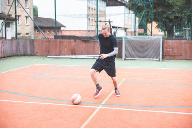 Genç adam dışarıda bir sahada futbol topunu kontrol etmeye odaklanıyor. Topla dikkatlice hokkabazlık yapıyor, etrafını binaların kentsel zeminiyle ve bir hedefle çeviriyor, spor ve becerileri birleştirerek..